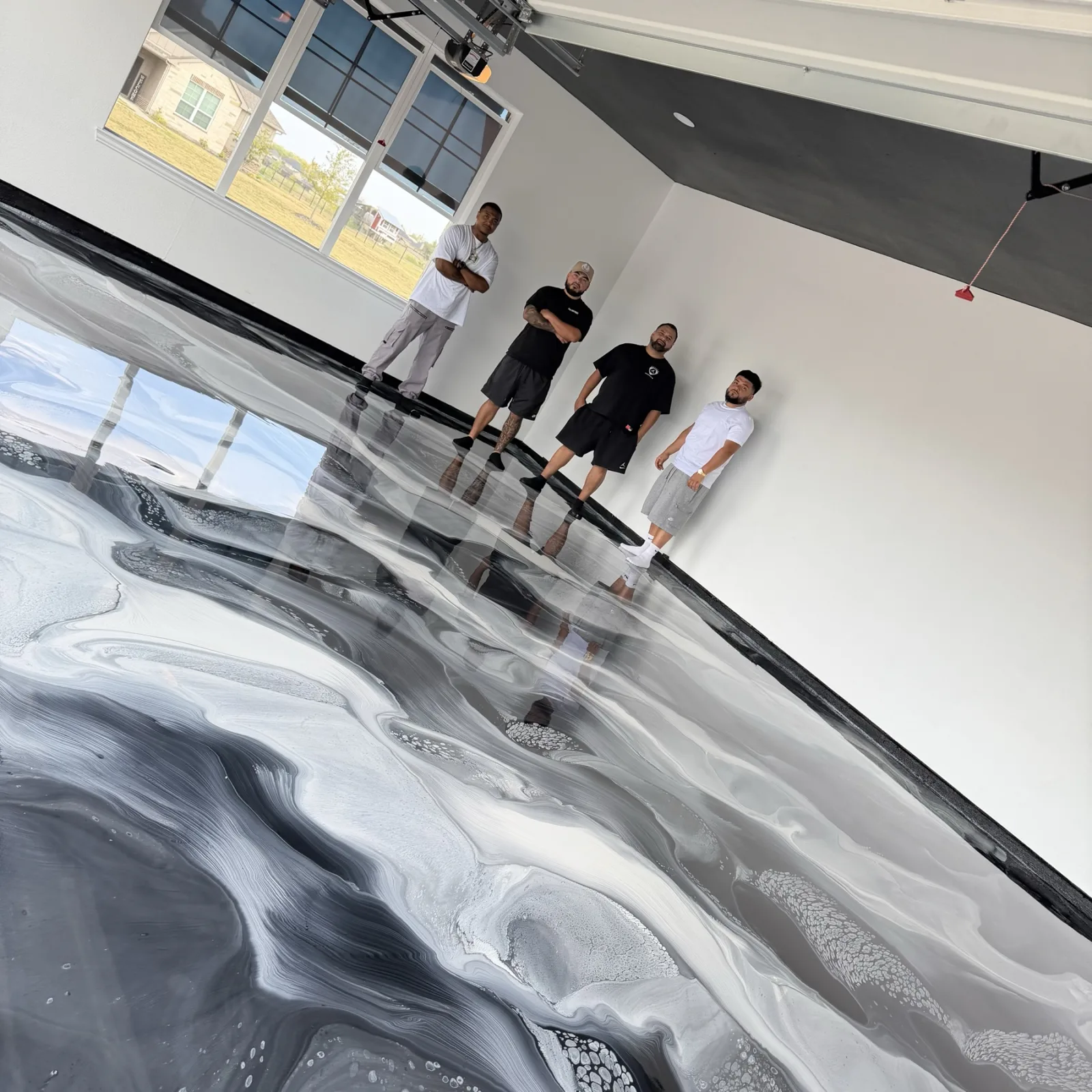 Four people standing beside the black, white, and grey metallic floor from a completed hands-on class.